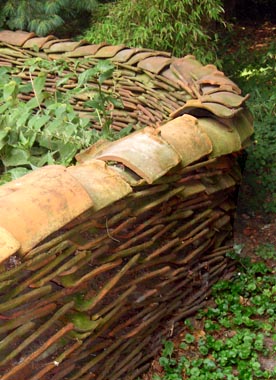 Alte Dachziegel zu einer frei stehenden Mauer im Garten aufgestapelt