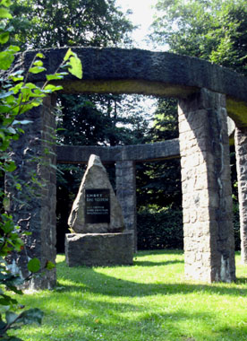 Ein Mahnmal aus großen Steinplatten, die im Kreis aufgestellt und von Büschen umgeben ist