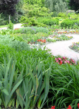 Stauden und Sommerblumen in Beeten, die von einem geschwungenen Weg durchzogen sind
