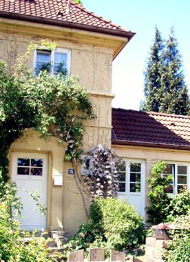Bildmotiv zur Steenkampsiedlung | Gartenstadt in Hamburg Ein hohes Wohnhaus mit Anbau, Sprossenfenster und grüne Rankpflanzen sorgen für ansprechende Optik