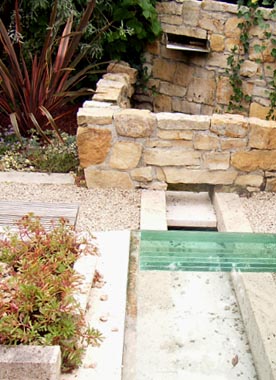 Bildmotiv zum Begriff "Senkgarten" Materialmix aus groben Steinen, Kies, exotischen Pflanzen und Glas im modernen Senkgarten